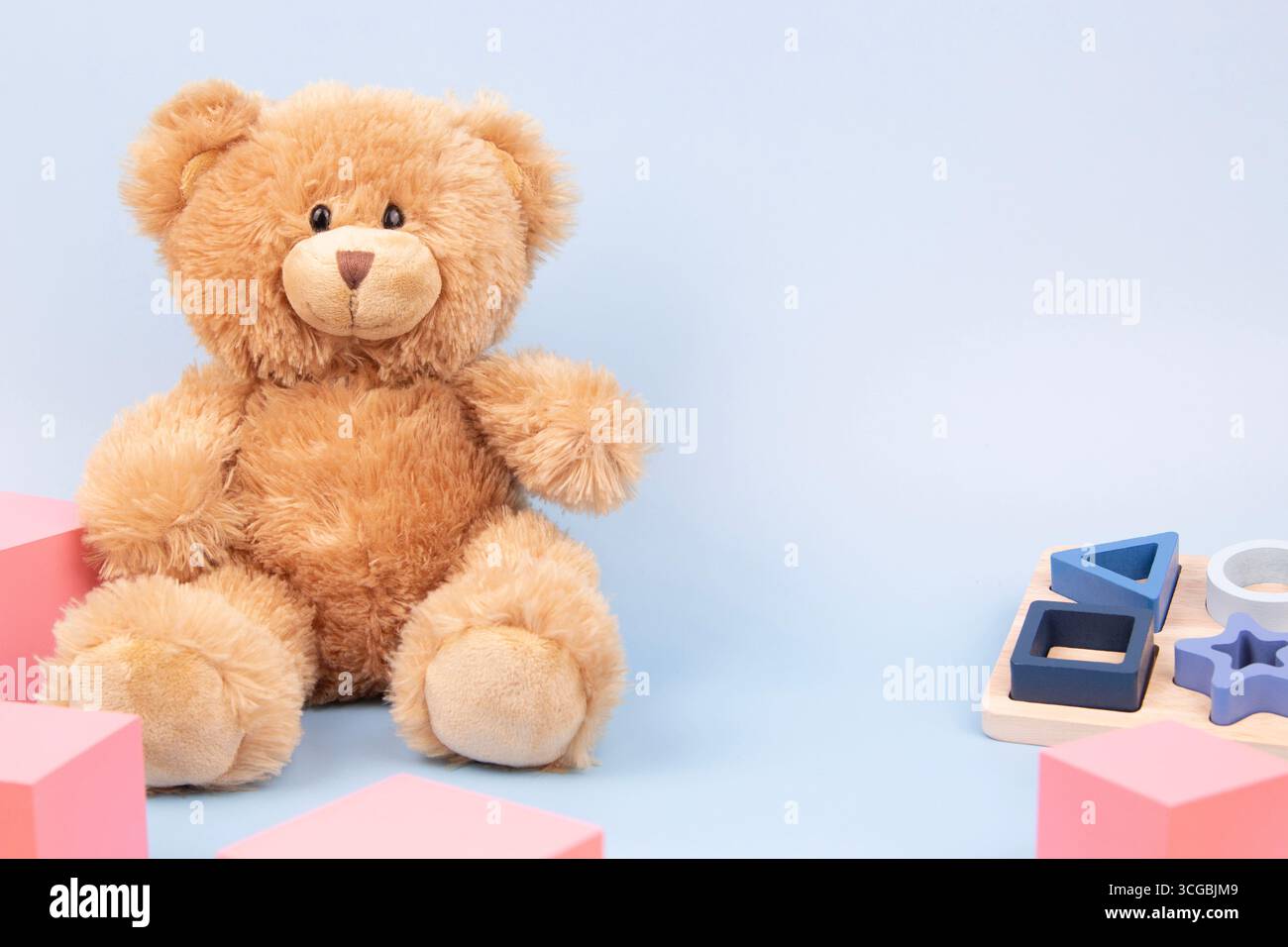 Fond de jouets pour enfants. Ours en peluche, empilement triant jouets sensoriels et cubes roses sur fond bleu. Jouets éducatifs Montessori pour enfants. Avant Banque D'Images