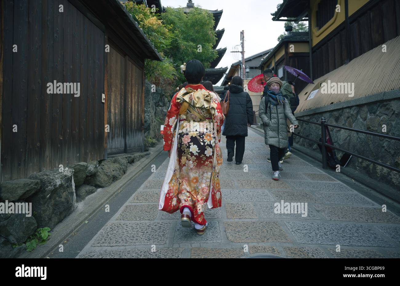 Femme dans un kimono vibrant marche vers la pagode Yasaka dans le quartier historique de Higashiyama à Kyoto Banque D'Images