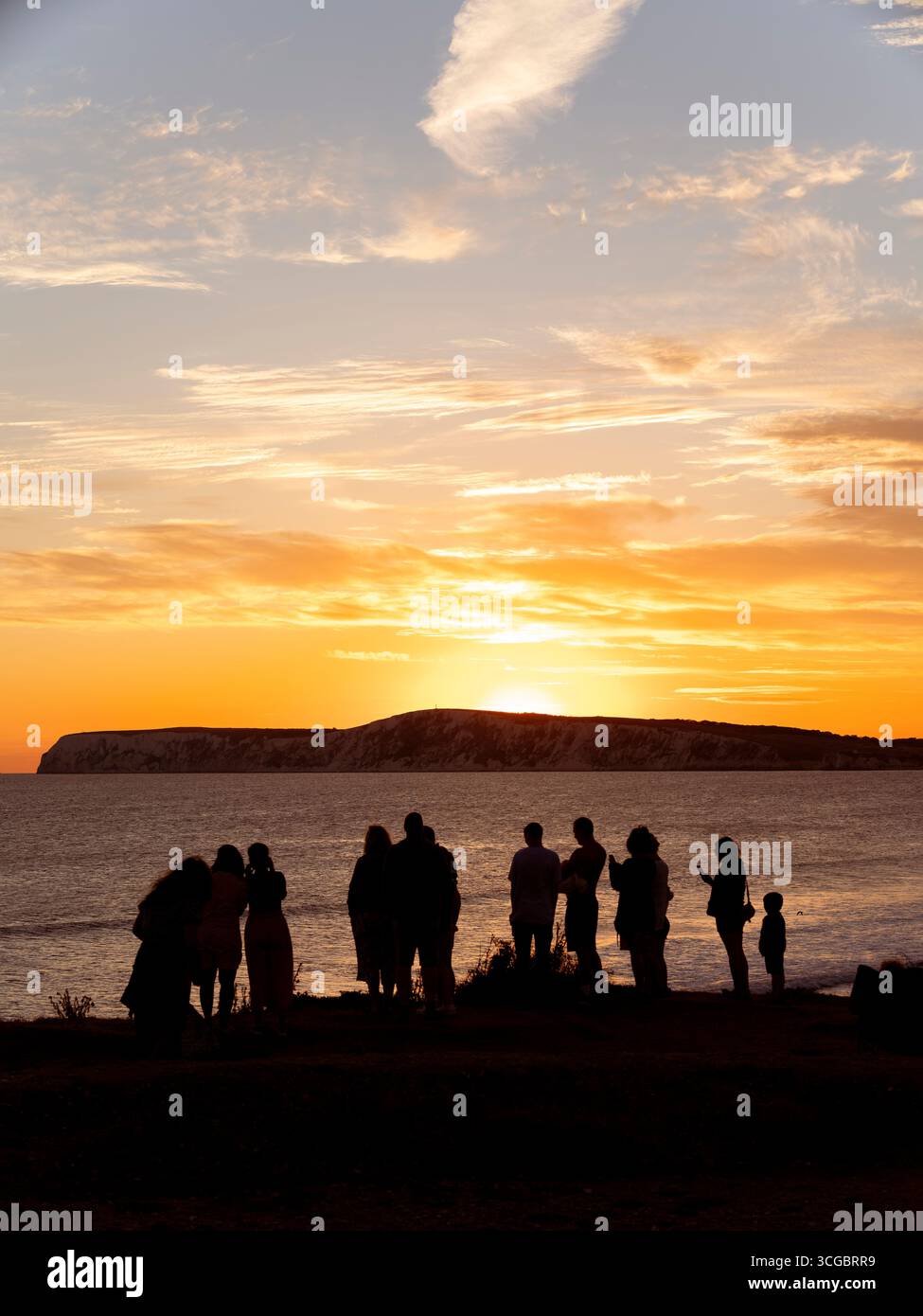 Silhouette de personnes regardant le coucher de soleil sur Compton Bay sur l'île de Wight un soir d'été. Banque D'Images