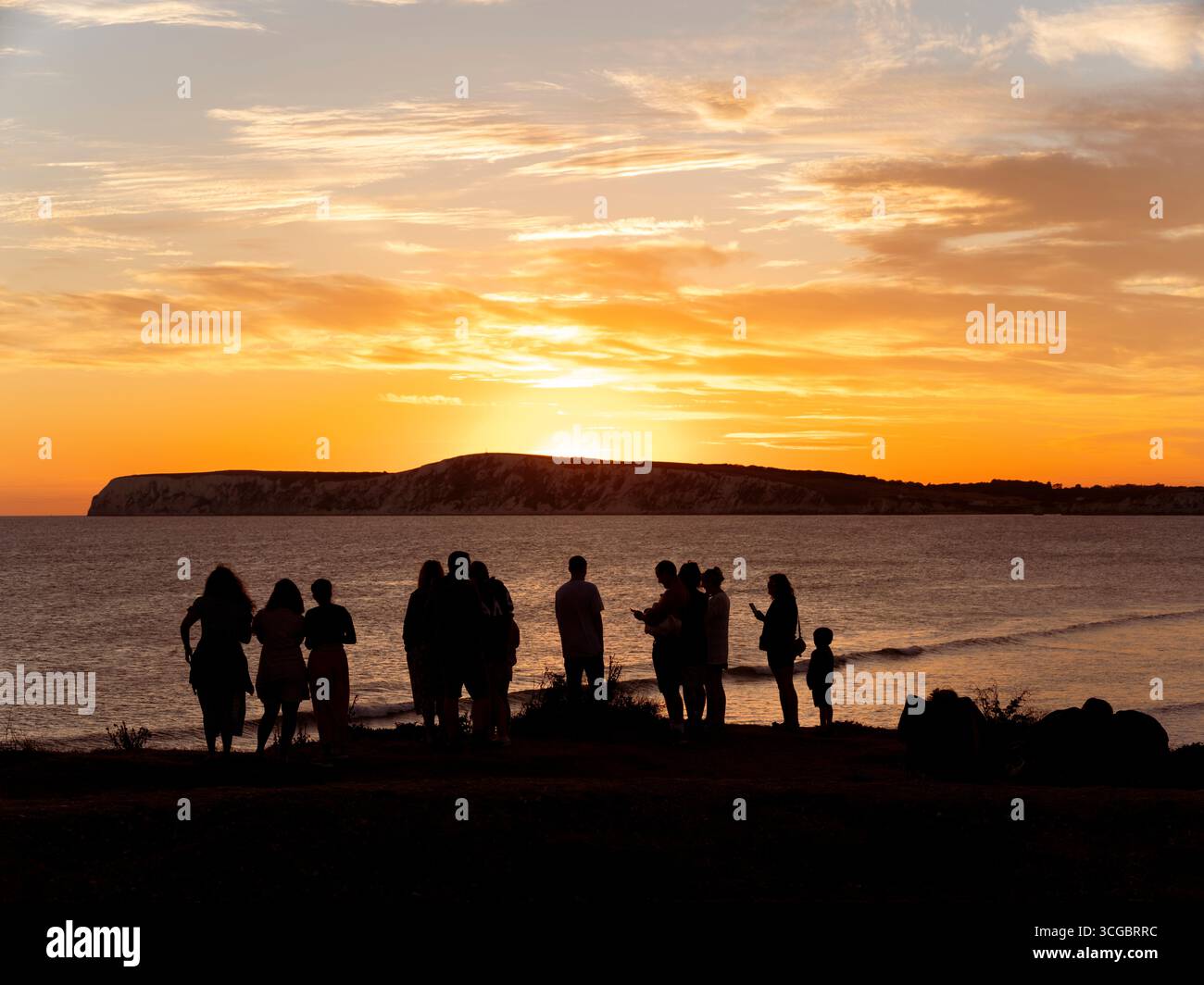 Silhouette de personnes regardant le coucher de soleil sur Compton Bay sur l'île de Wight un soir d'été. Banque D'Images