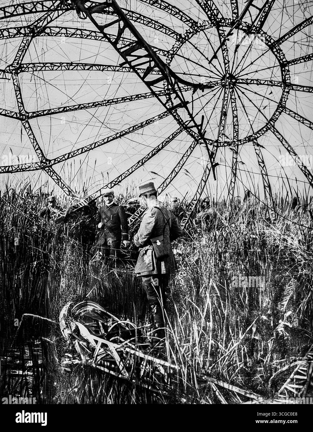 Des officiers français inspectent les restes squelettiques d'un Zeppelin allemand descendu dans les marais du Vardar, 1916. La vaste structure en aluminium du dirigeable s'élève au-dessus des roseaux, illustrant à la fois l'immense échelle et la fragilité de ces premières armes de guerre aérienne. L'image reflète le choc destructeur de la technologie moderne sur le front des Balkans pendant la première Guerre mondiale Banque D'Images