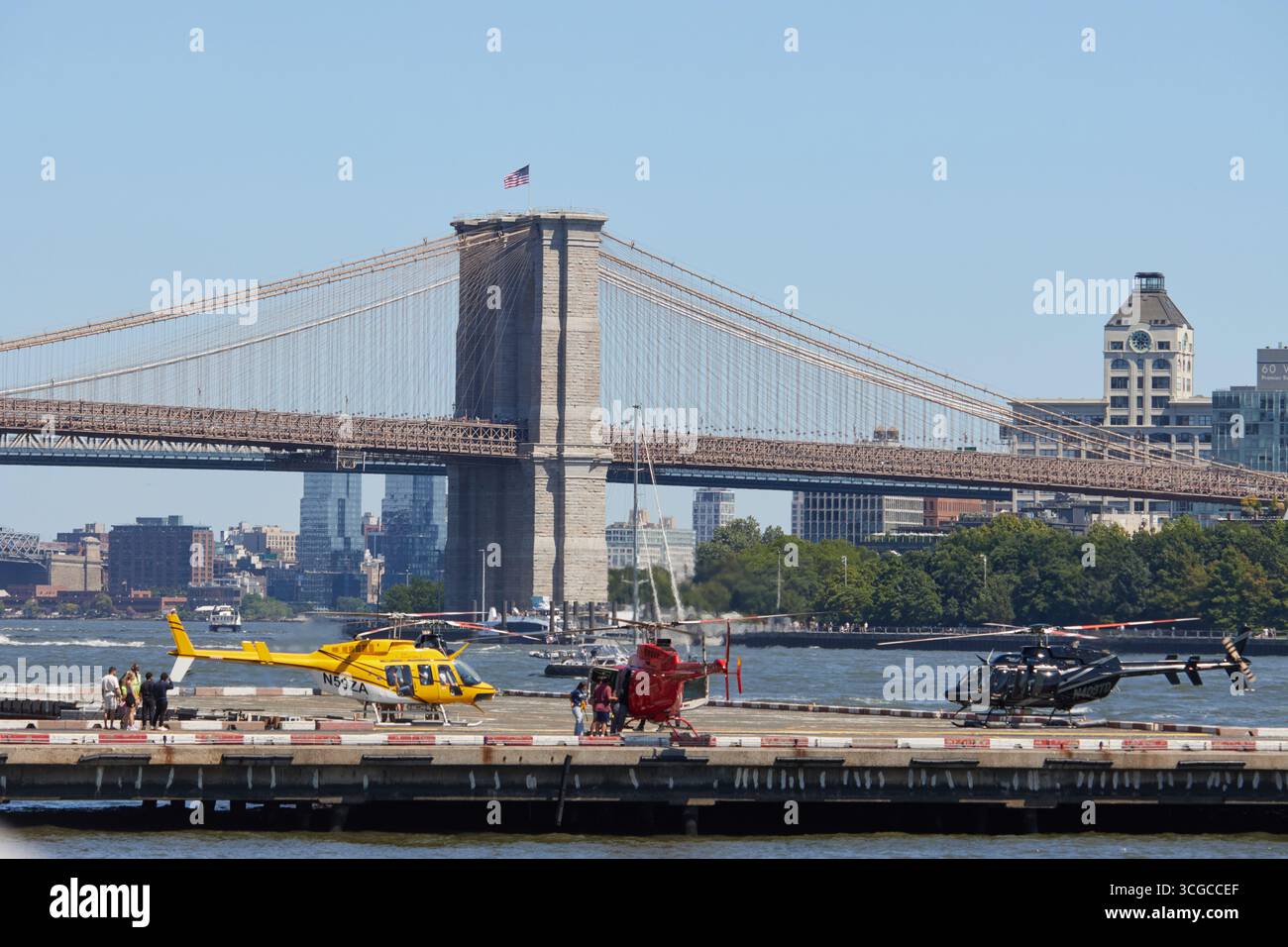 Hélicoptères en héliport avec des personnes embarquant au Downtown Skyport dans le port de New York avec le pont de Brooklyn par une journée ensoleillée d'été, espace copie Banque D'Images