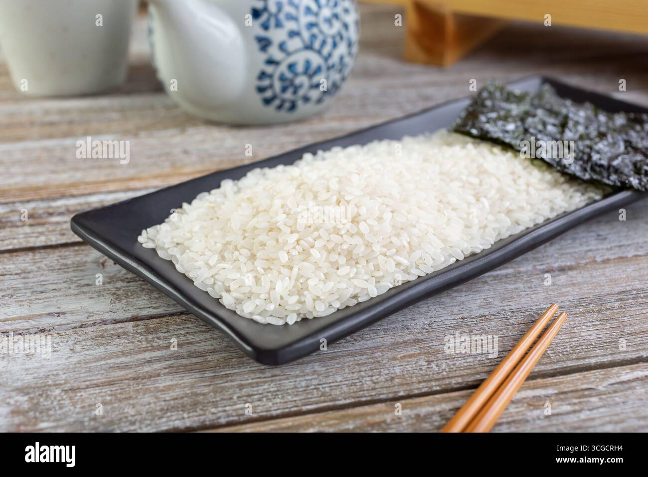 Une vue d'un plat noir avec du riz à sushi ou du riz à grains courts, dans un cadre de nature morte. Banque D'Images