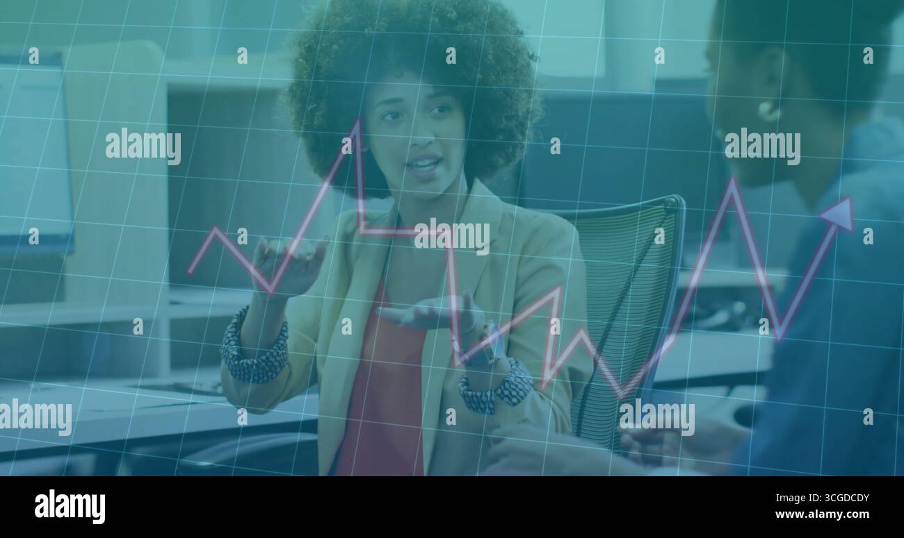 Femme gestuelle en blazer beige et chemisier rouge analysant les données, avec graphique linéaire superposé dans le bureau Banque D'Images