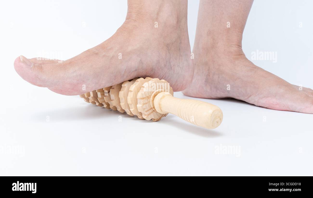 Le masseur à rouleaux de pied est pressé contre les pieds fatigués, offrant un soulagement apaisant et un confort après une longue position debout ou une marche, parfait pour relaxa Banque D'Images