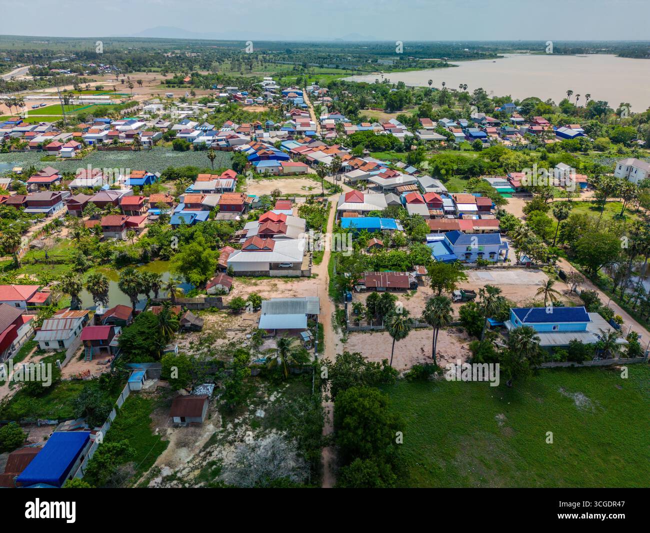 Vue drone du village de Krang Thnong avec des toits colorés, des terres agricoles et un lac à proximité dans le district de Bati, province de Takeo, Cambodge. L'image montre tra Banque D'Images