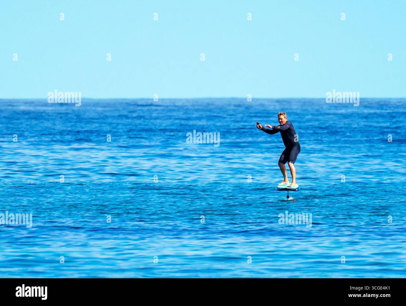 Un homme sur une planche de surf e foil au large de la plage de Beadnell dans le Northumberland, au Royaume-Uni. Banque D'Images