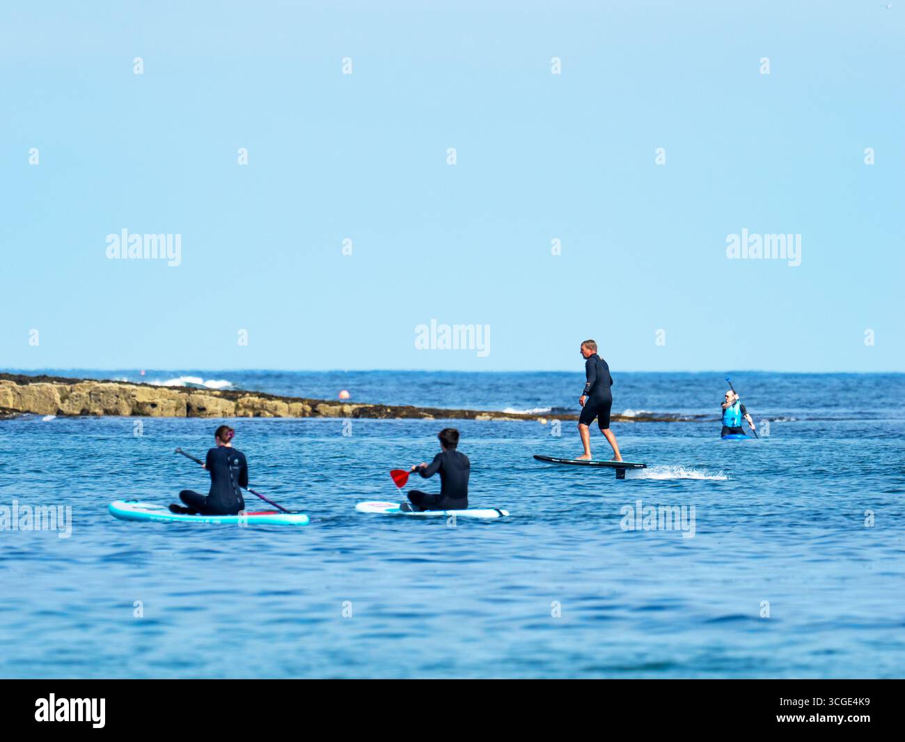 Un homme sur une planche de surf e foil au large de la plage de Beadnell dans le Northumberland, au Royaume-Uni. Banque D'Images