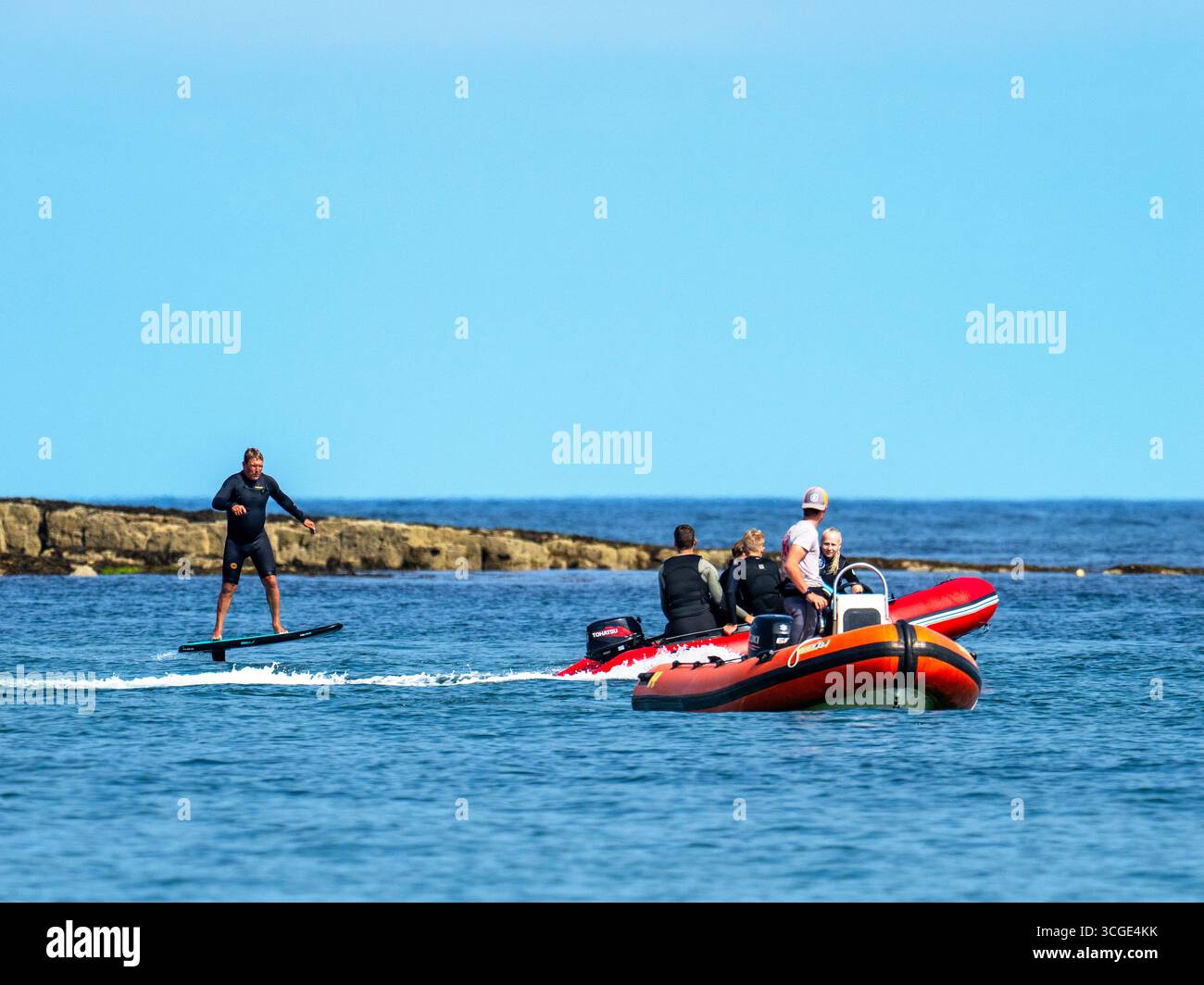 Un homme sur une planche de surf e foil au large de la plage de Beadnell dans le Northumberland, au Royaume-Uni. Banque D'Images