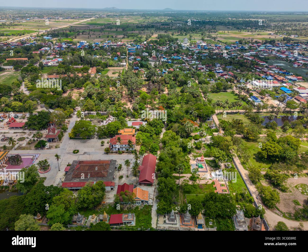 Vue par drone d'un complexe de pagodes bouddhistes avec des maisons environnantes, de la verdure et des terres agricoles près du lac Tonlé Bati dans la province de Takeo, au Cambodge. La scène salut Banque D'Images