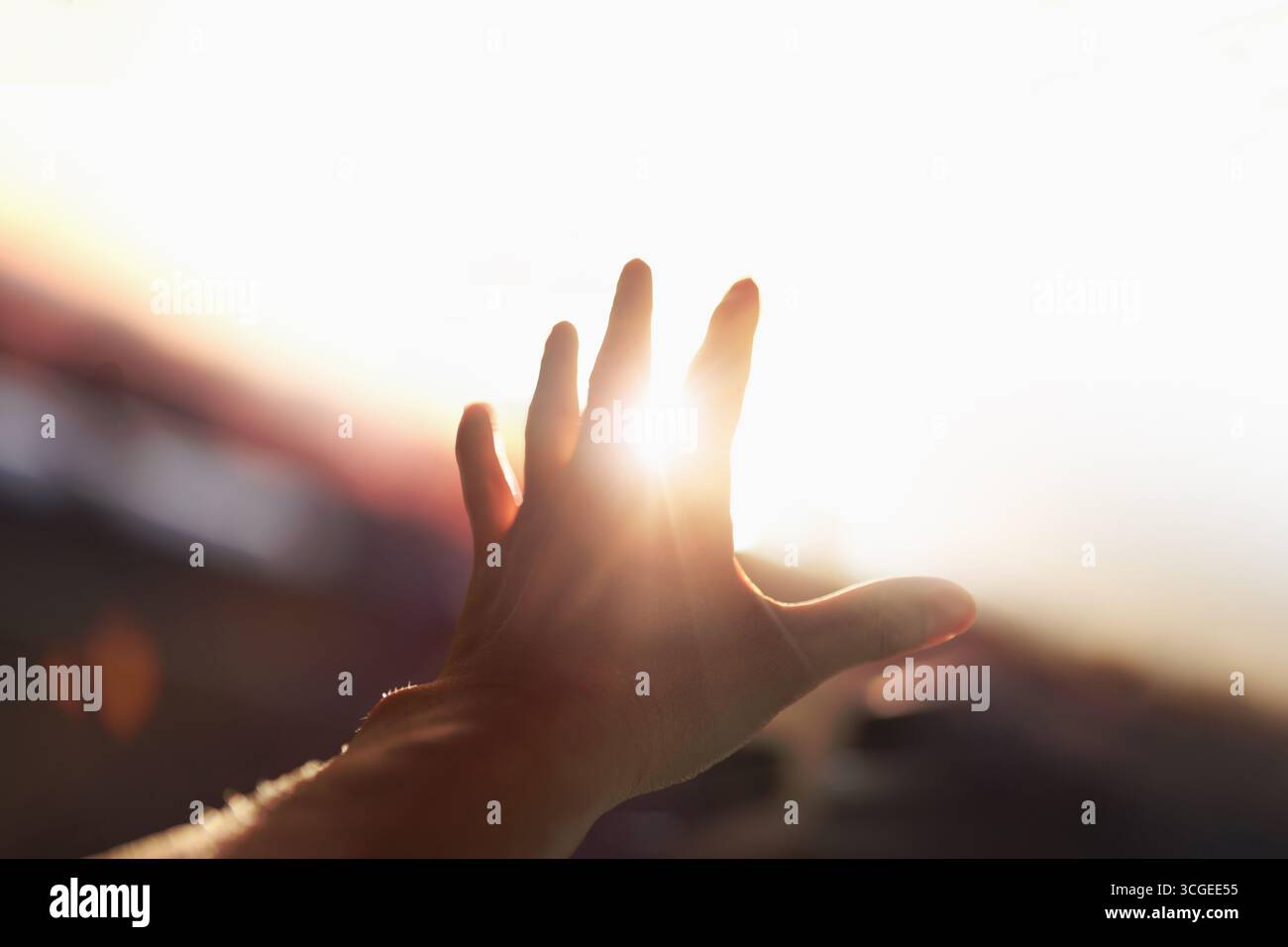Un faisceau lumineux fort et brillant brillant à travers les bras et les doigts s'étendait vers le soleil brillant. Banque D'Images