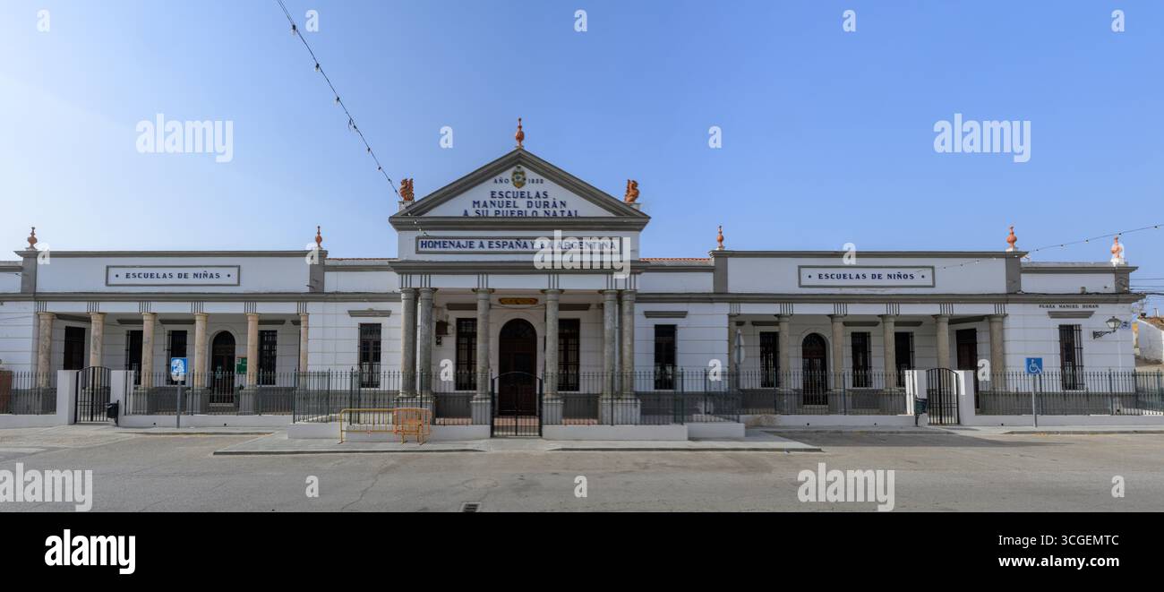 Construite en 1930, cette école néoclassique en Estrémadure reflète la fierté locale de Puebla del Maestre, célébrant les liens culturels. Banque D'Images
