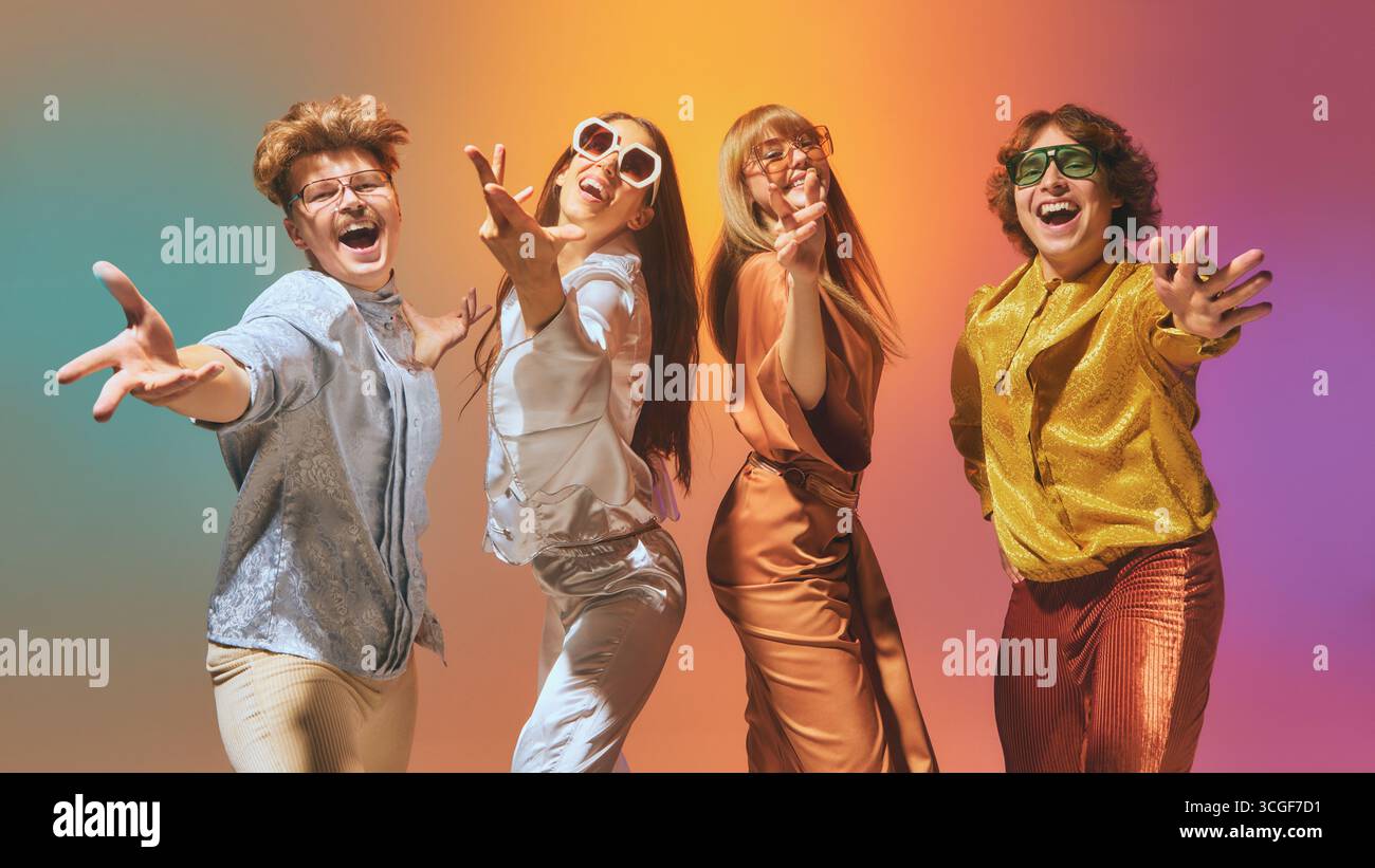Groupe de quatre personnes de style vintage dansant dans une lumière disco avec des tenues rétro expressives Banque D'Images