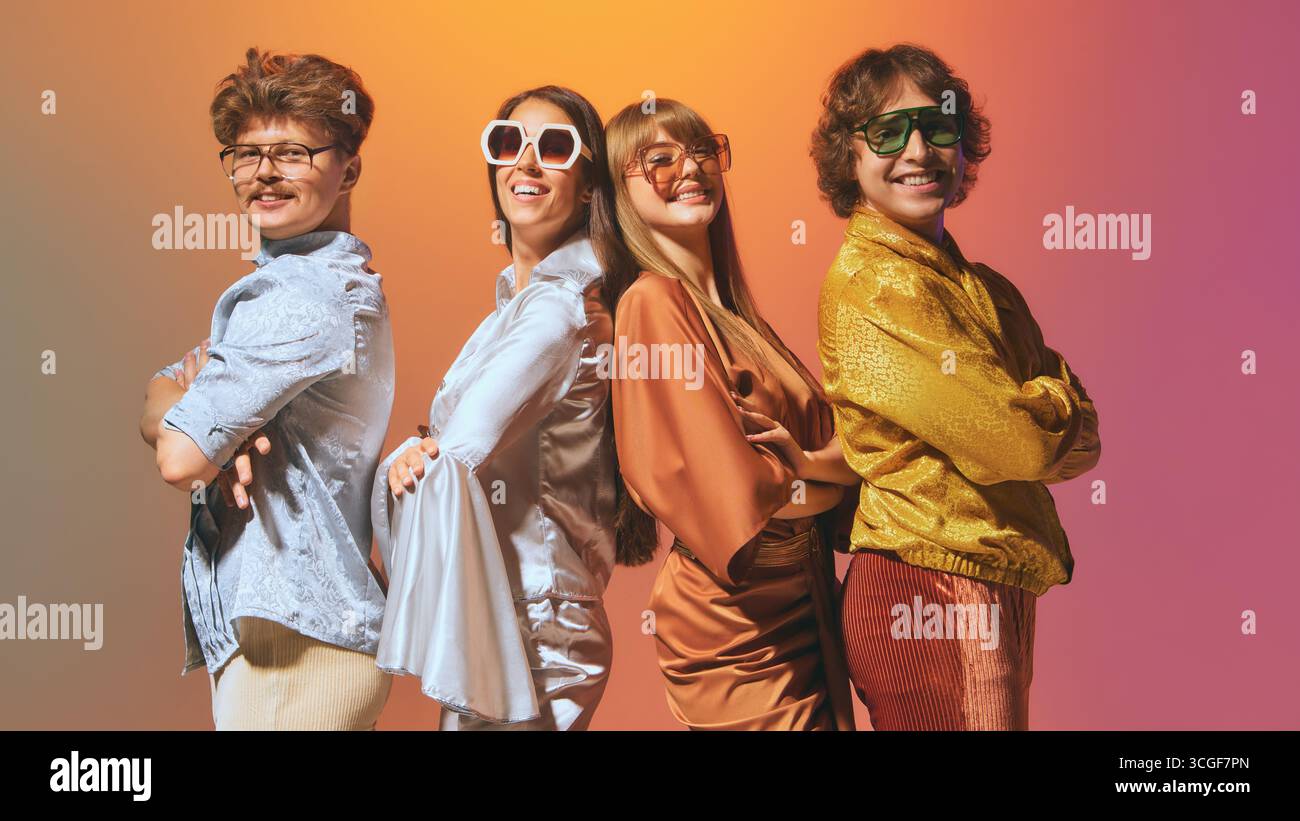 Amis debout dos à dos dans des tenues de mode vintage souriant Banque D'Images