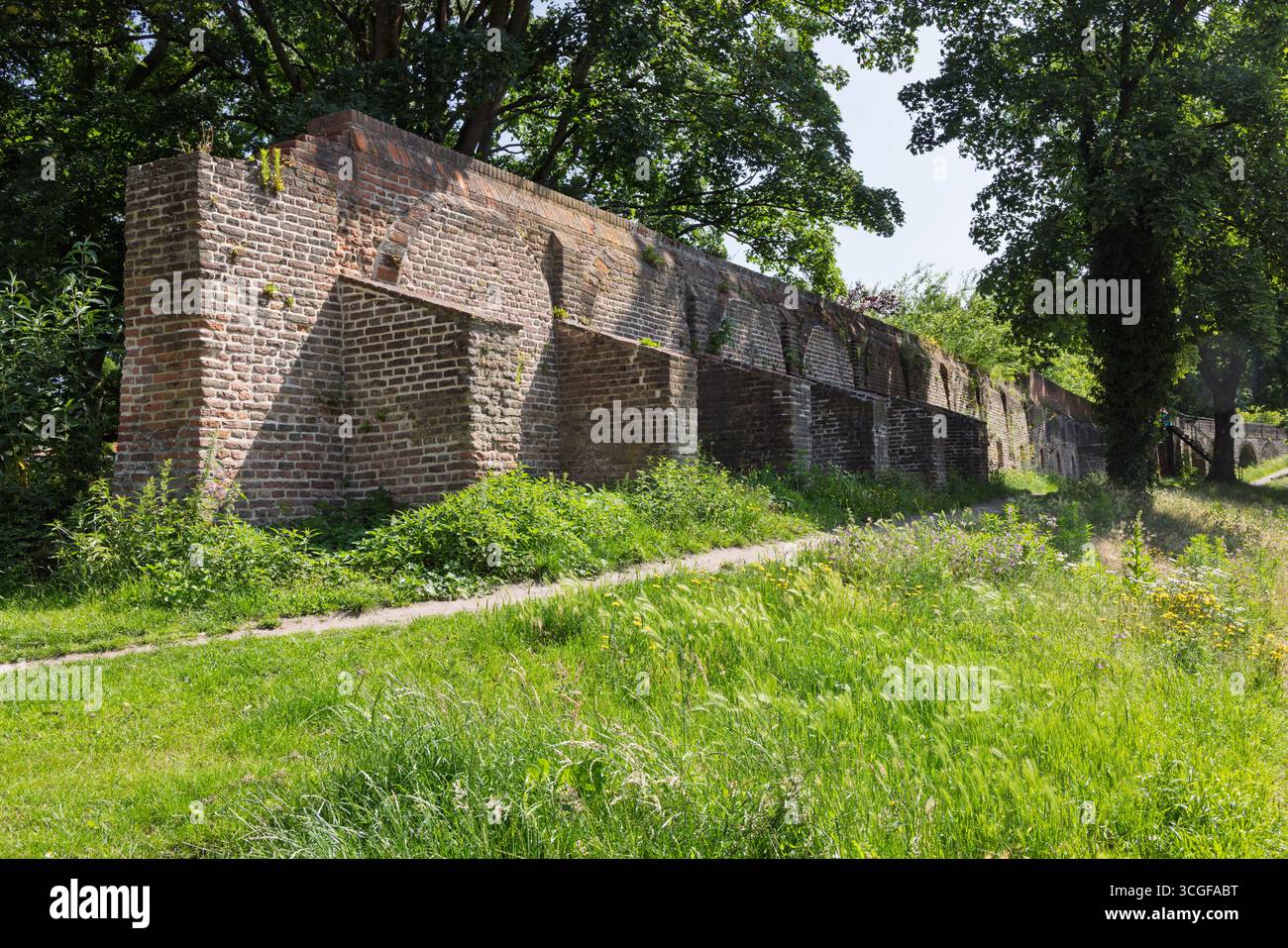 Une ancienne structure de mur de briques, faisant partie des fortifications de la vieille ville, se dresse au milieu de l'herbe verte luxuriante et des arbres matures à Amersfoort. Banque D'Images