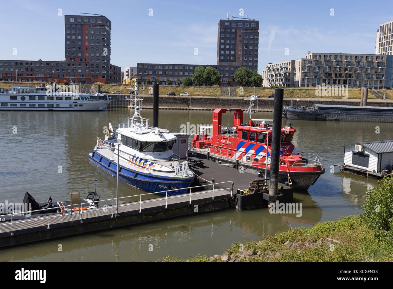 Deux bateaux de sauvetage amarrés, un bateau de pompiers et un bateau de police, sont assis sur la rivière Waal à Nimègue avec des appartements modernes en arrière-plan. Nimègue, Netherla Banque D'Images