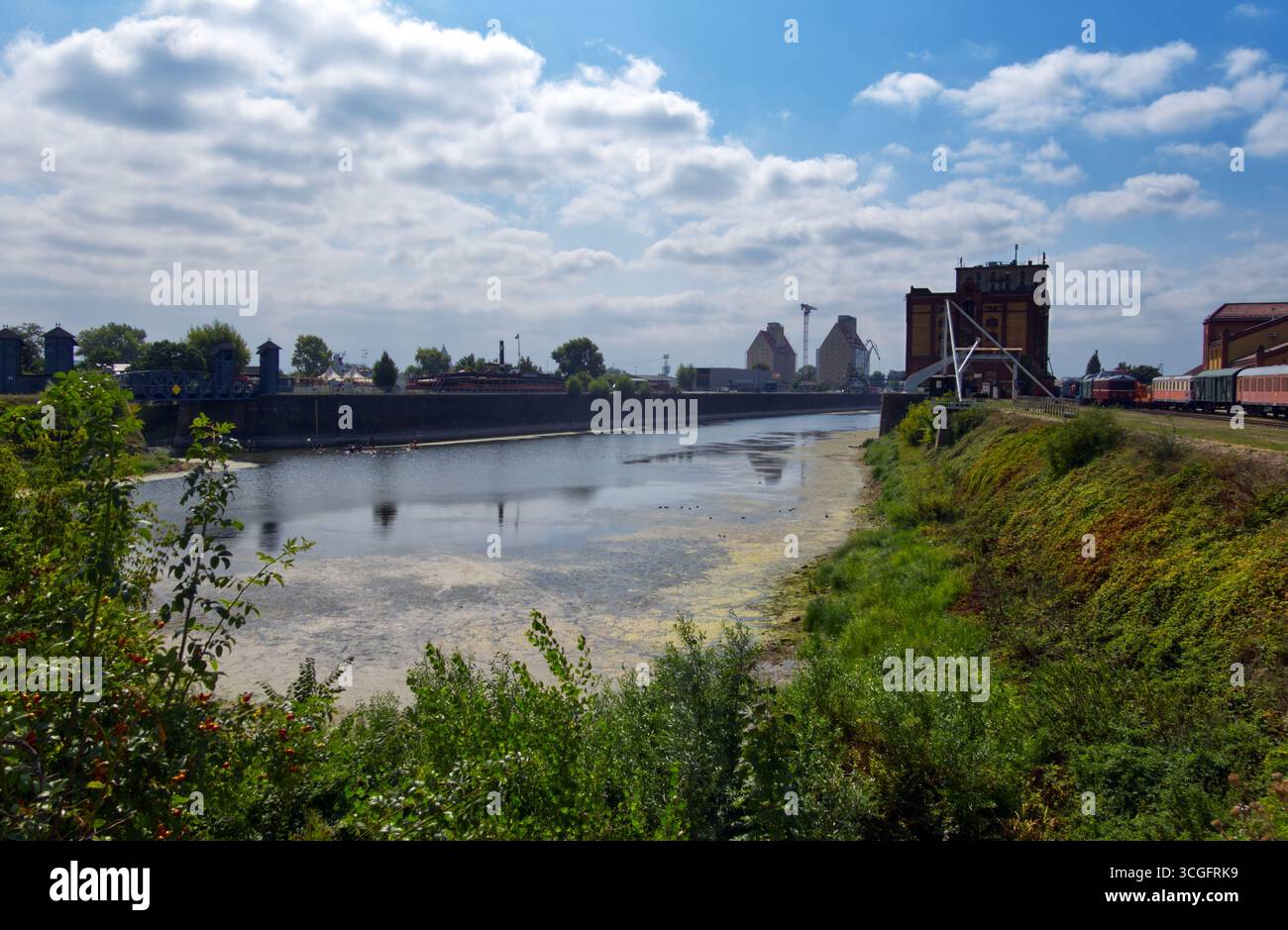 Canal Elbe-havel traversant le port historique de magdebourg, structures industrielles encadrant le passage à niveau dans des conditions météorologiques nuageuses Banque D'Images