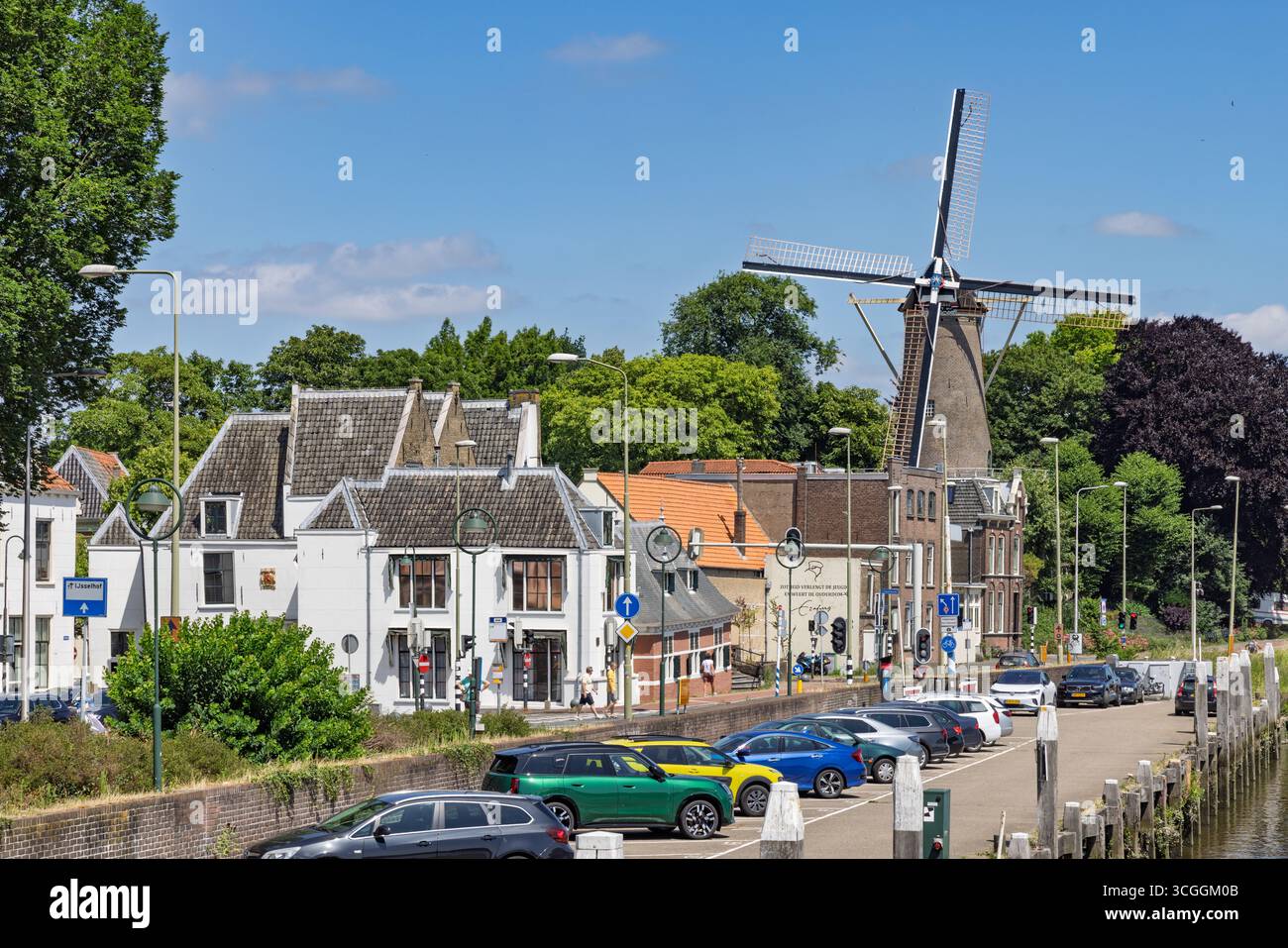 Un moulin à vent hollandais classique ''t Slot' se dresse au milieu de maisons traditionnelles le long d'un canal à Gouda, sous un ciel bleu, capturant un paysage hollandais. Gouda, Banque D'Images
