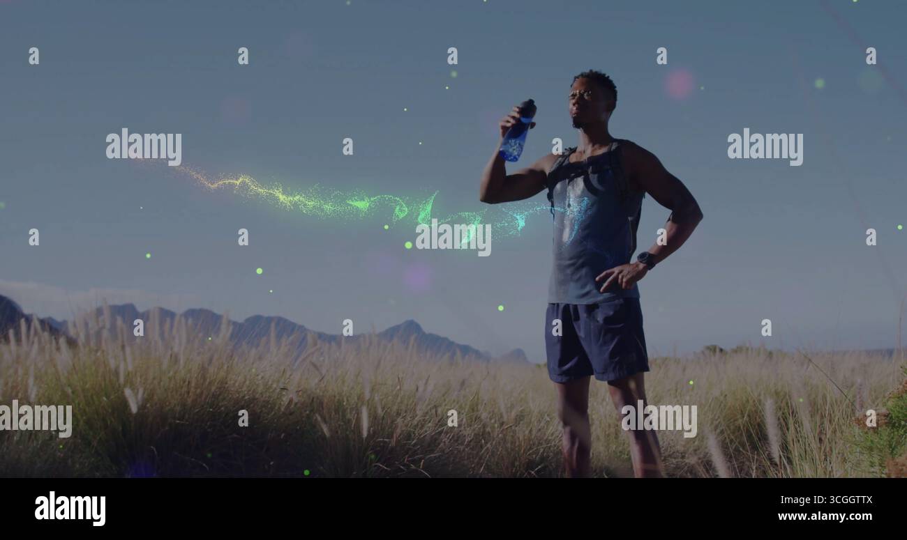 Coureur portant des vêtements de sport et un pack d'hydratation au pied de la colline, avec montre et bouteille d'eau bleue Banque D'Images