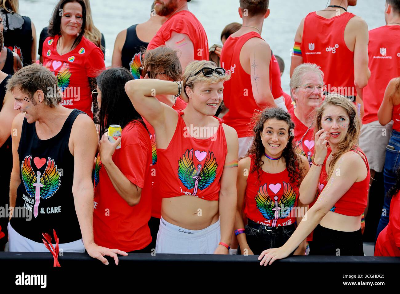 Pride Amsterdam canal Parade les participants en chemises rouges amour et soin sourient sur un bateau sur l'eau à Amsterdam, aux pays-Bas, pendant l'événement estival. Banque D'Images