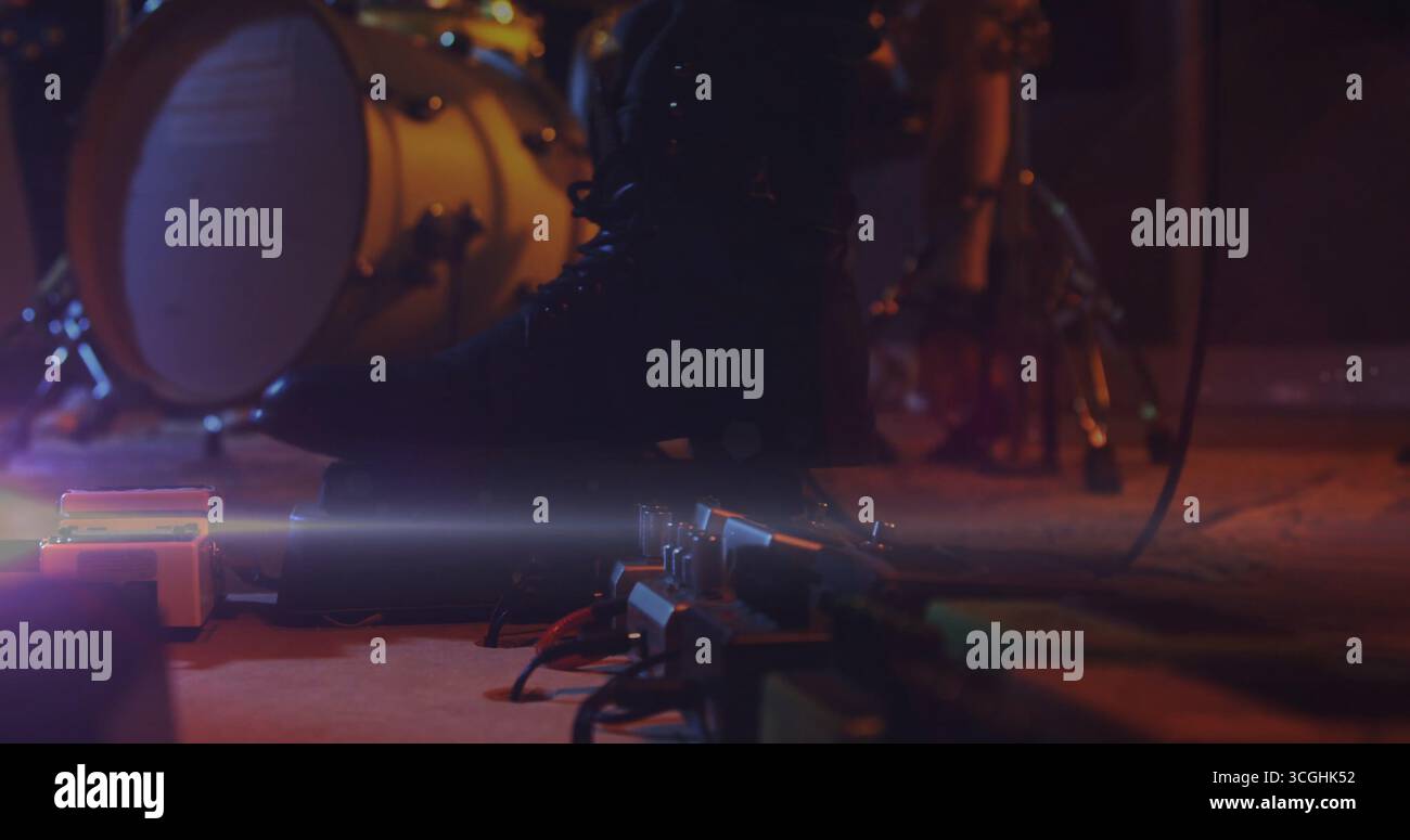 Botte en cuir de musicien activant les pédales de guitare sur scène, avec grosse caisse et câbles audio Banque D'Images