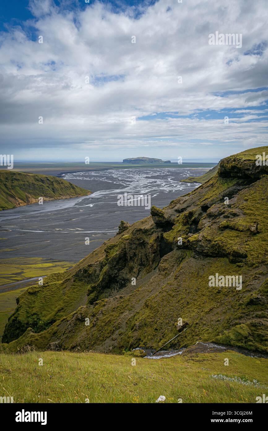 Vue surélevée sur les falaises couvertes de mousse surplombant les canaux fluviaux tressés qui coulent à travers une plaine de sable noir en Islande Banque D'Images