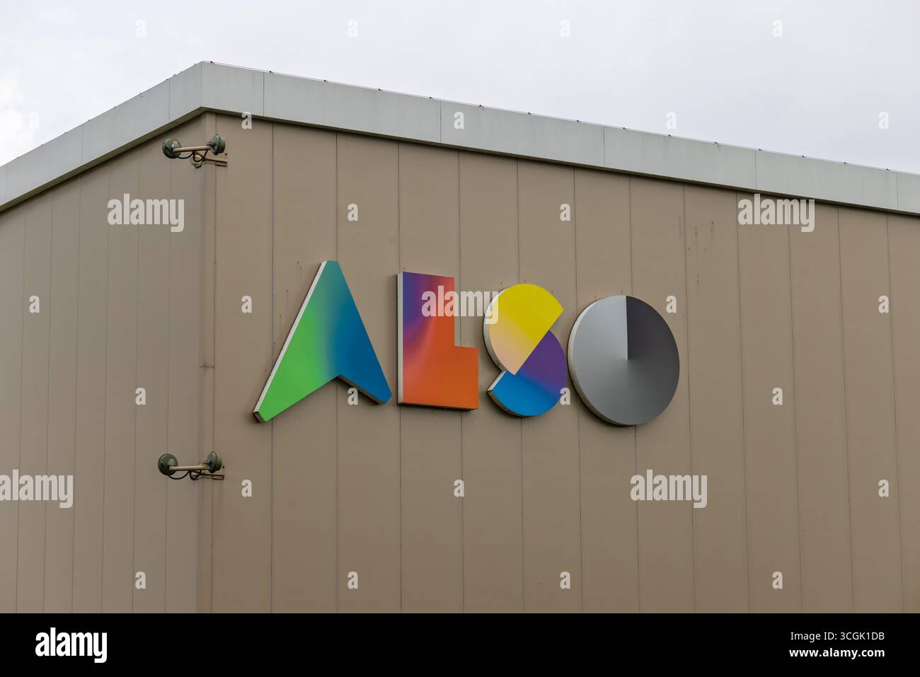 Le logo vibrant et multicolore « ALSO » est affiché en évidence sur la façade brun clair d'un bâtiment d'entreprise moderne sous un ciel nuageux, avec une str Banque D'Images