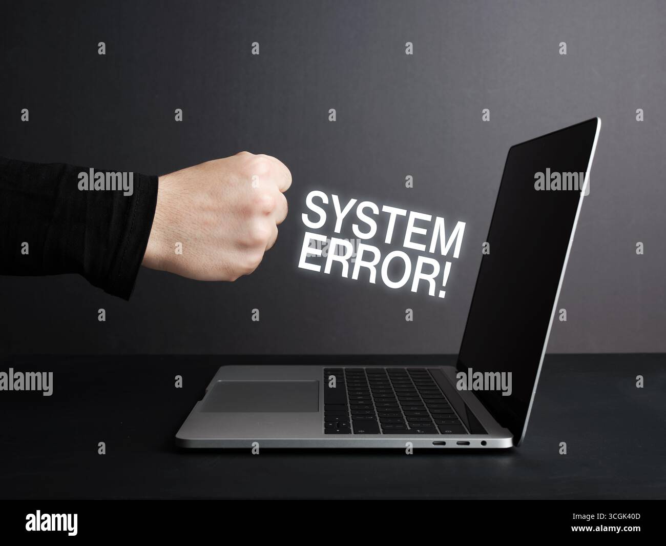 Coup de poing sur un ordinateur portable montrant un message d'erreur système sur l'écran, exprimant la frustration et la colère à propos des problèmes informatiques Banque D'Images
