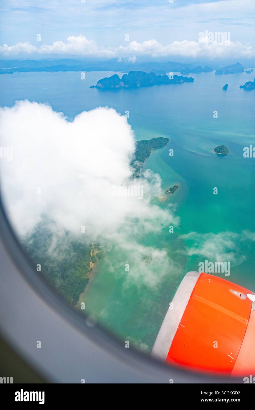 Vue aérienne depuis la fenêtre de l'avion montrant les îles tropicales, la mer turquoise et les nuages avec le moteur de l'avion. Paysage pittoresque symbolisant le voyage, vacati Banque D'Images Vue aérienne depuis la fenêtre de l'avion montrant les îles tropicales, la mer turquoise et les nuages avec le moteur de l'avion. Paysage pittoresque symbolisant le voyage, vacati Banque D'Images