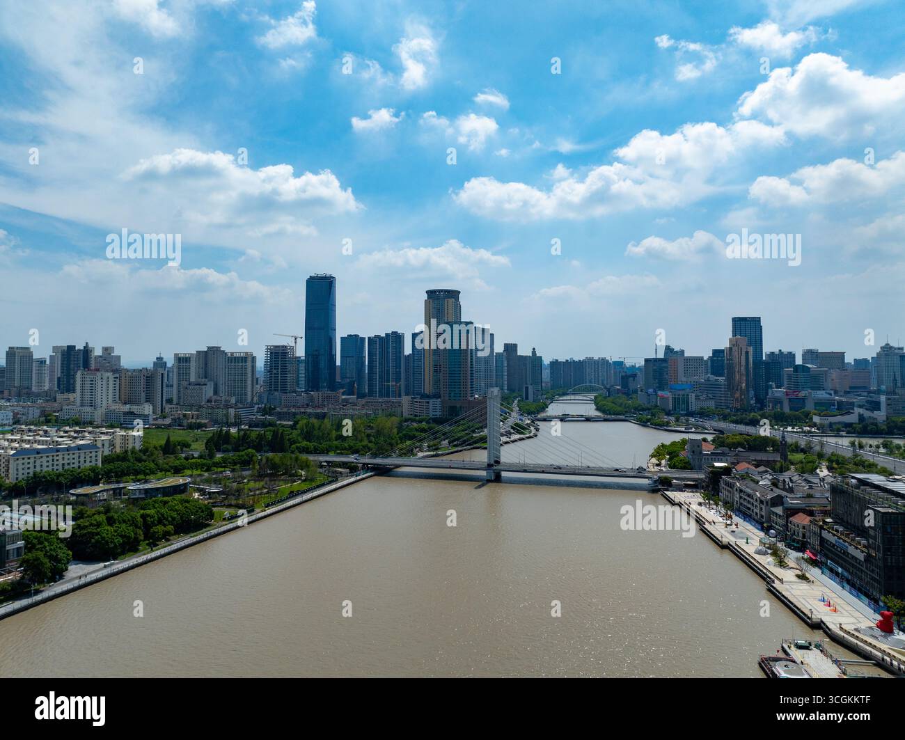Vue panoramique de la ville de Ningbo en Chine avec une large rivière qui coule devant des gratte-ciels modernes et des ponts sous un ciel bleu. Banque D'Images