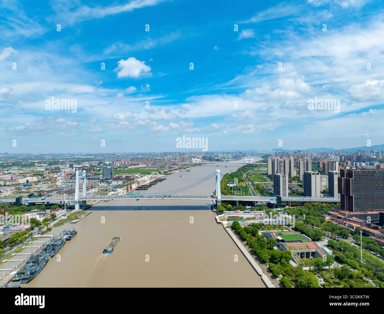 Ville de Ningbo, Chine, vista montre une large rivière, un grand pont et des bâtiments. Le développement urbain s'étend sous un ciel bleu vif. Banque D'Images