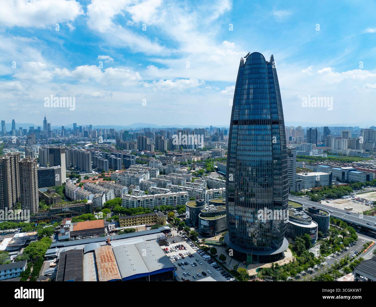 Un gratte-ciel moderne s'élève bien au-dessus du vaste paysage urbain de la ville de Ningbo, en Chine, sous un ciel bleu clair. Banque D'Images