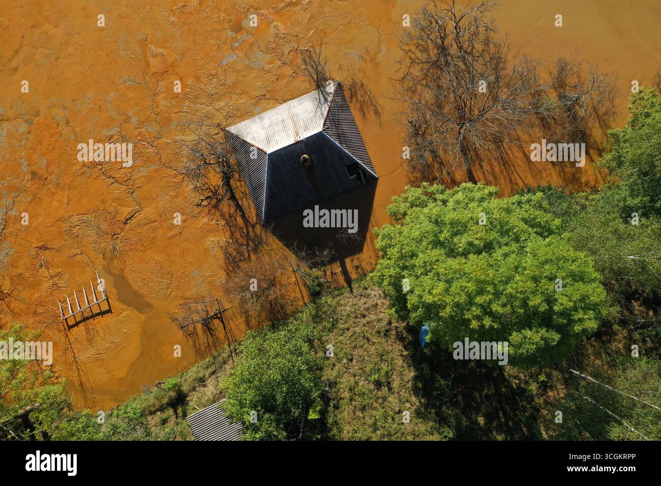 Vue aérienne de la maison de village en train de couler au milieu du lac de décantation de mines toxiques Banque D'Images