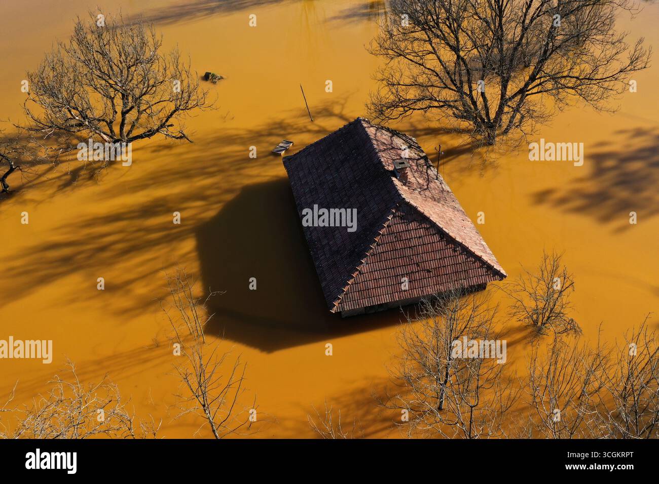 Vue aérienne de la maison de village en train de couler au milieu du lac de décantation de mines toxiques Banque D'Images