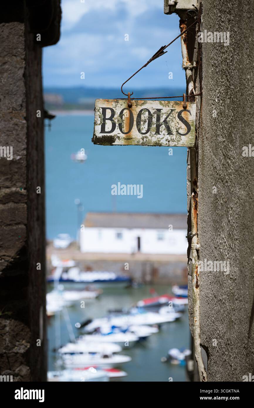 Une vieille enseigne, des livres publicitaires, accrochée à un mur de magasin, surplombant un littoral idylique Banque D'Images