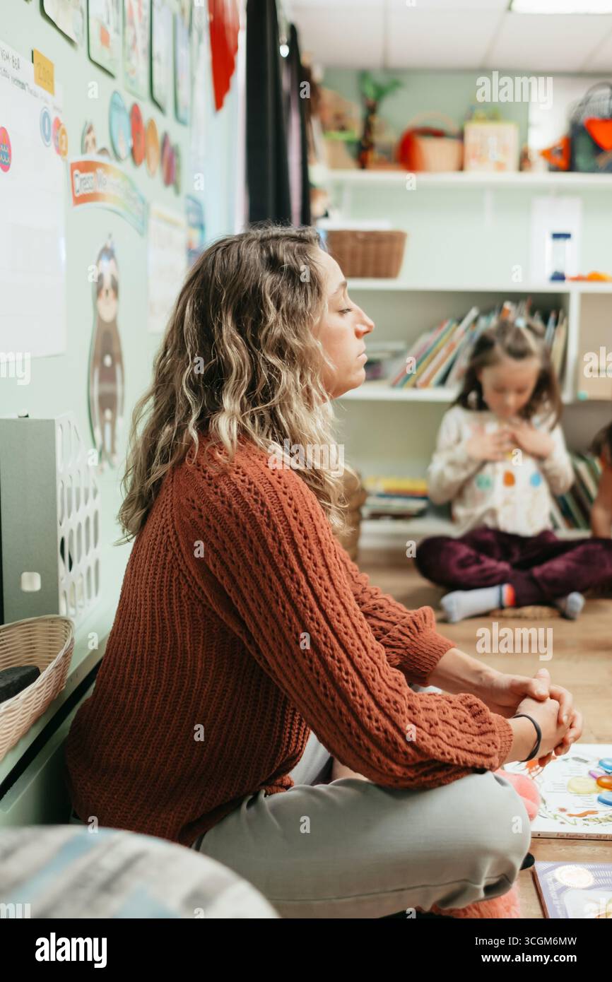 Enseignant pratiquant la pleine conscience avec les enfants en classe préscolaire Banque D'Images