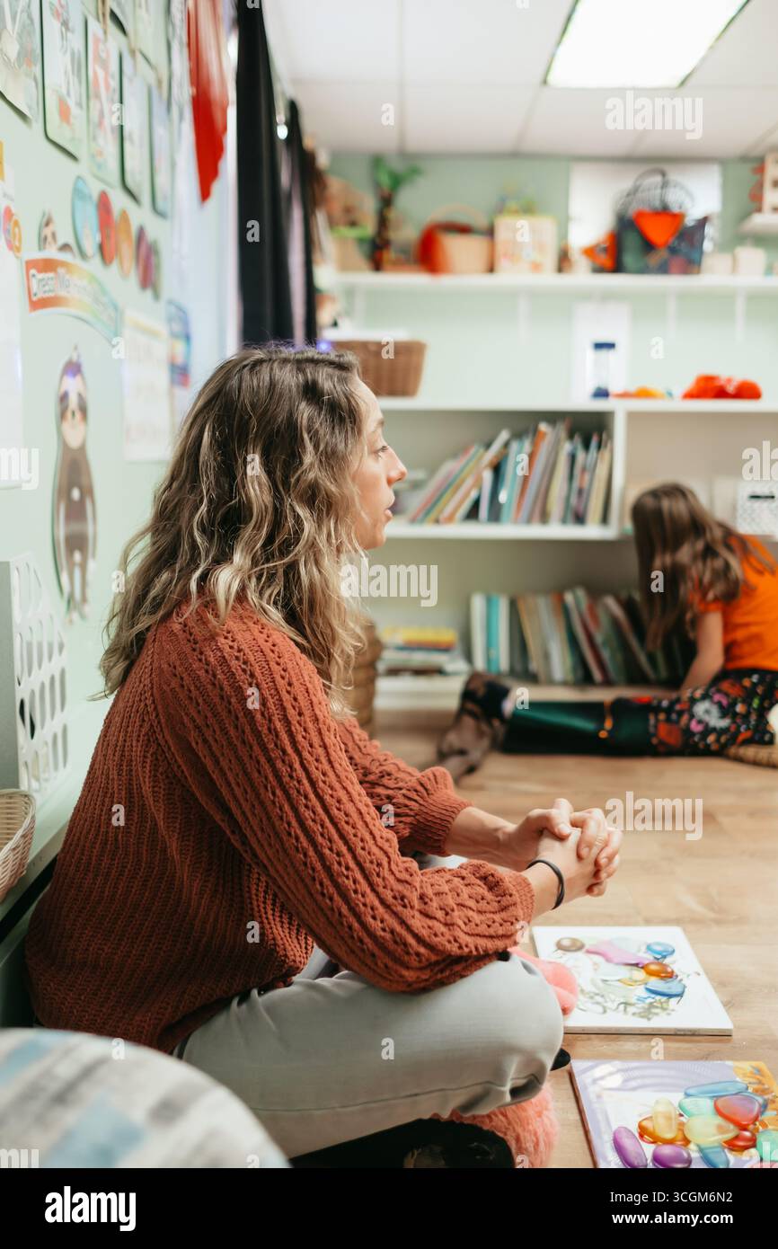 Professeur regardant les élèves jouer dans la salle de classe préscolaire montessori Banque D'Images