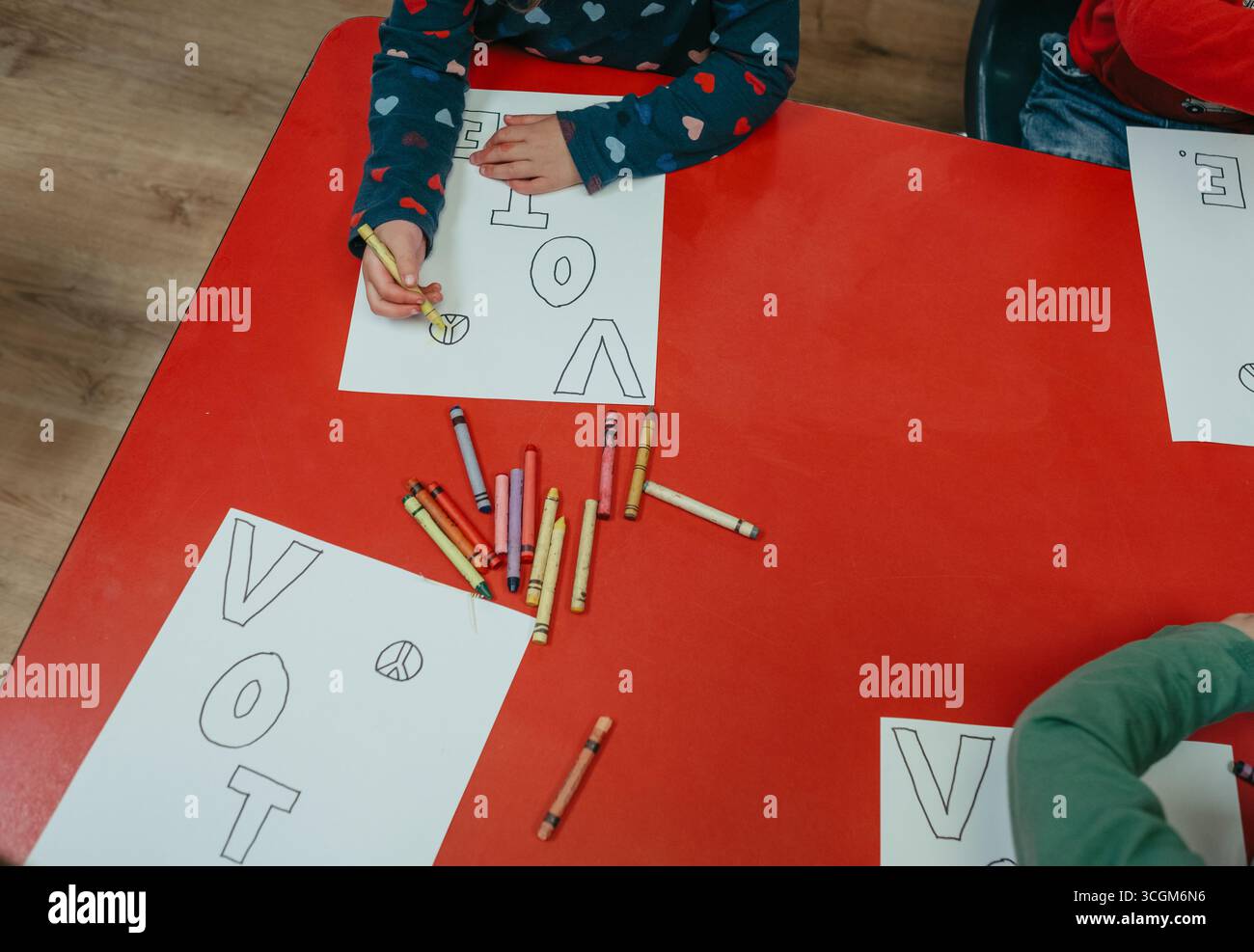 Les enfants d'âge préscolaire colorent les symboles de paix et le mot vote Banque D'Images