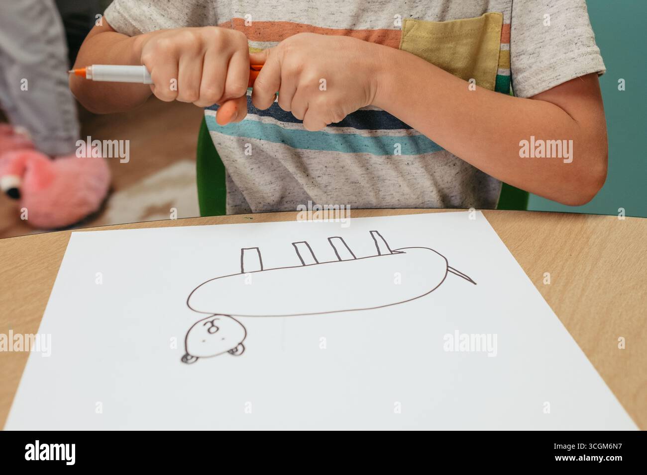 Enfant d'âge préscolaire ouvrant stylo feutre orange se préparant à dessiner sur papier Banque D'Images