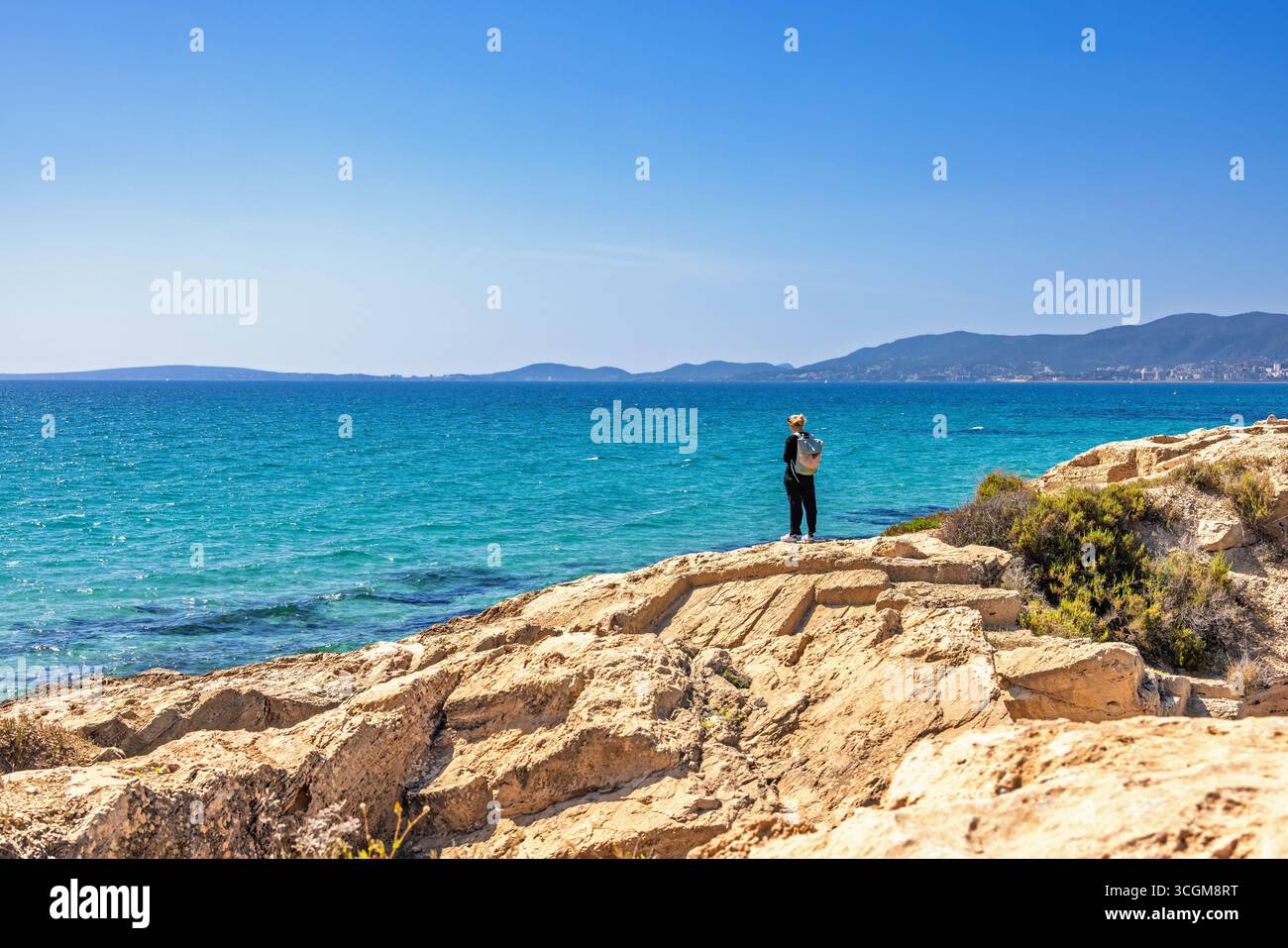 Seule jeune femme debout sur un rocher au bord de la mer méditerranée une journée d'été ensoleillée Banque D'Images