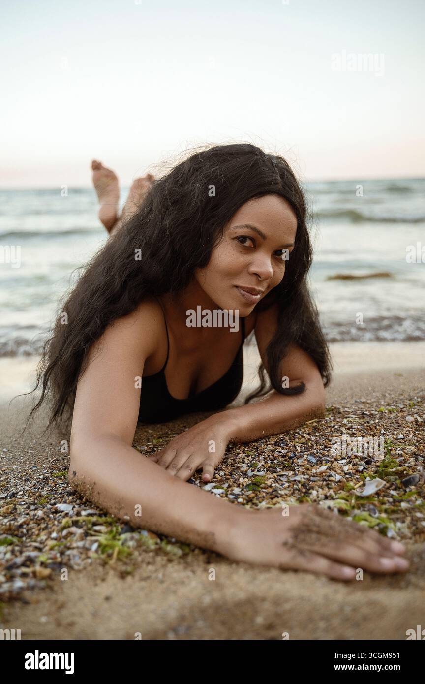 Femme afro-américaine allongée sur la plage de la mer Banque D'Images