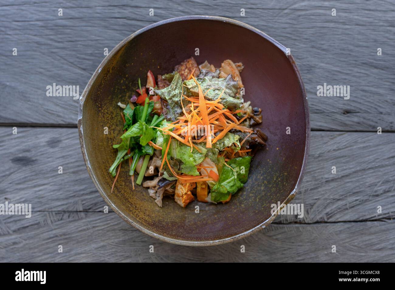 Salade biologique de riz vert curry, aubergines, kimchi, légumes verts braisés, champignons, tempeh bacon, tofu est servi dans un bol en argile. Gros plan. Le concept de Banque D'Images