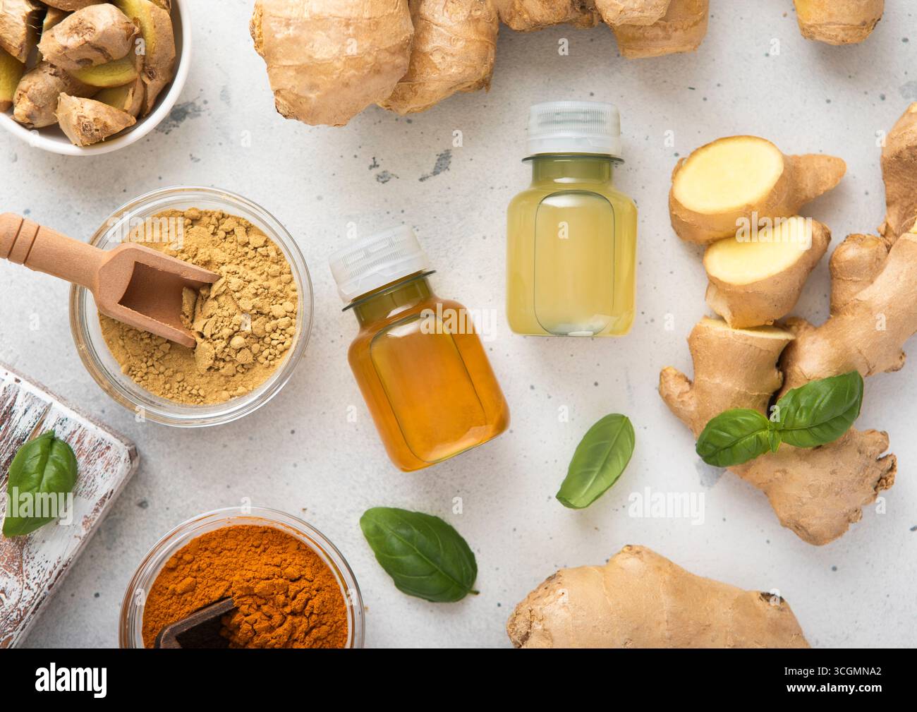 Bouteilles de boisson de tir d'énergie de curcuma immunitaire au gingembre avec des racines de gingembre crues fraîches et des fruits d'oranges sur fond clair. Banque D'Images
