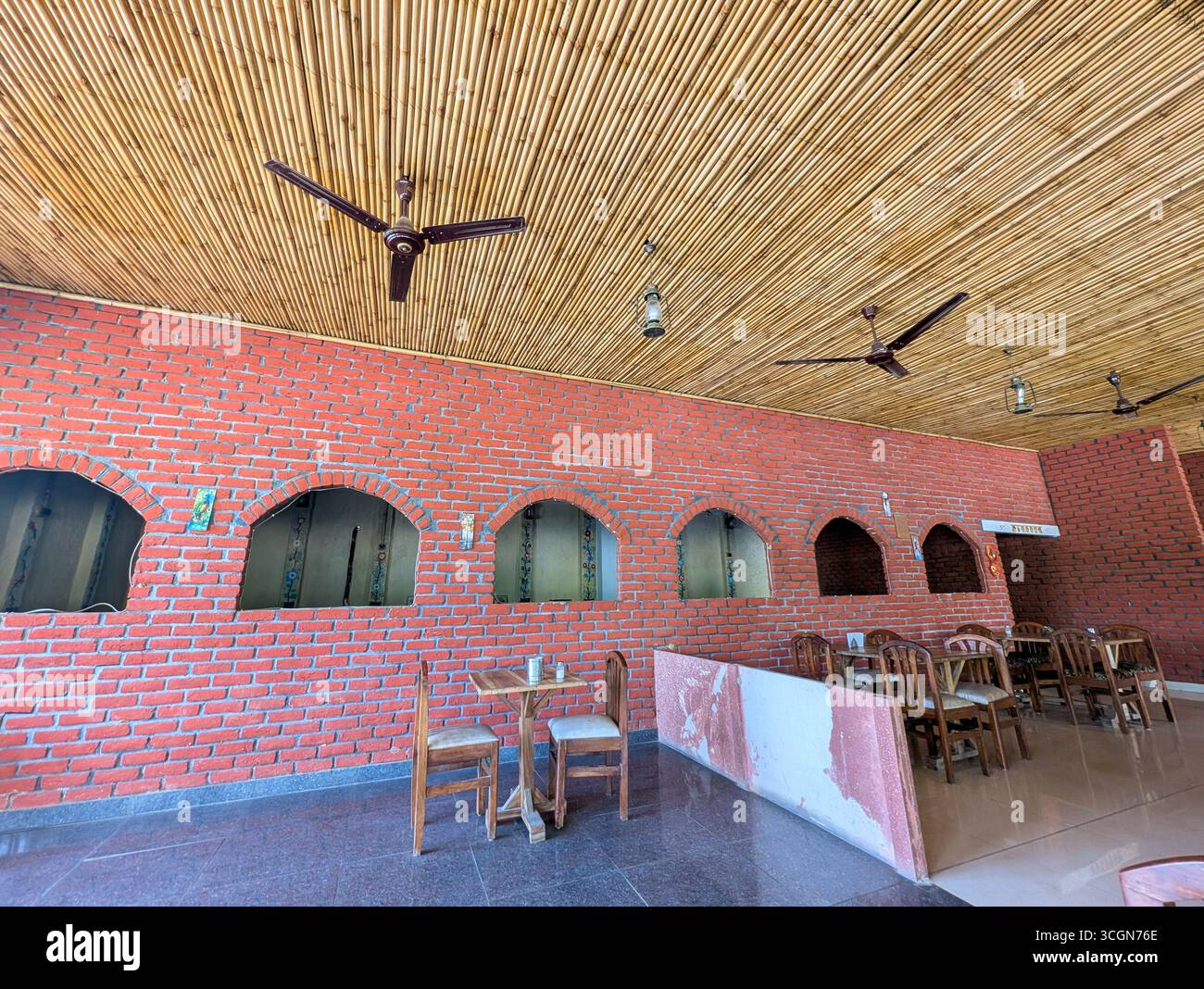 Avril13th2025 Dehradun Uttarakhand Inde. Intérieur rustique du restaurant avec murs en briques, plafond en bois et mobilier en bois simple. Banque D'Images