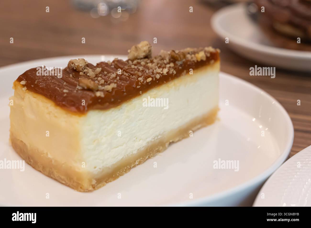 Dégustez un cheesecake crémeux garni de glaçage au caramel et de noix croquantes, rehaussant sa texture délicieuse Banque D'Images