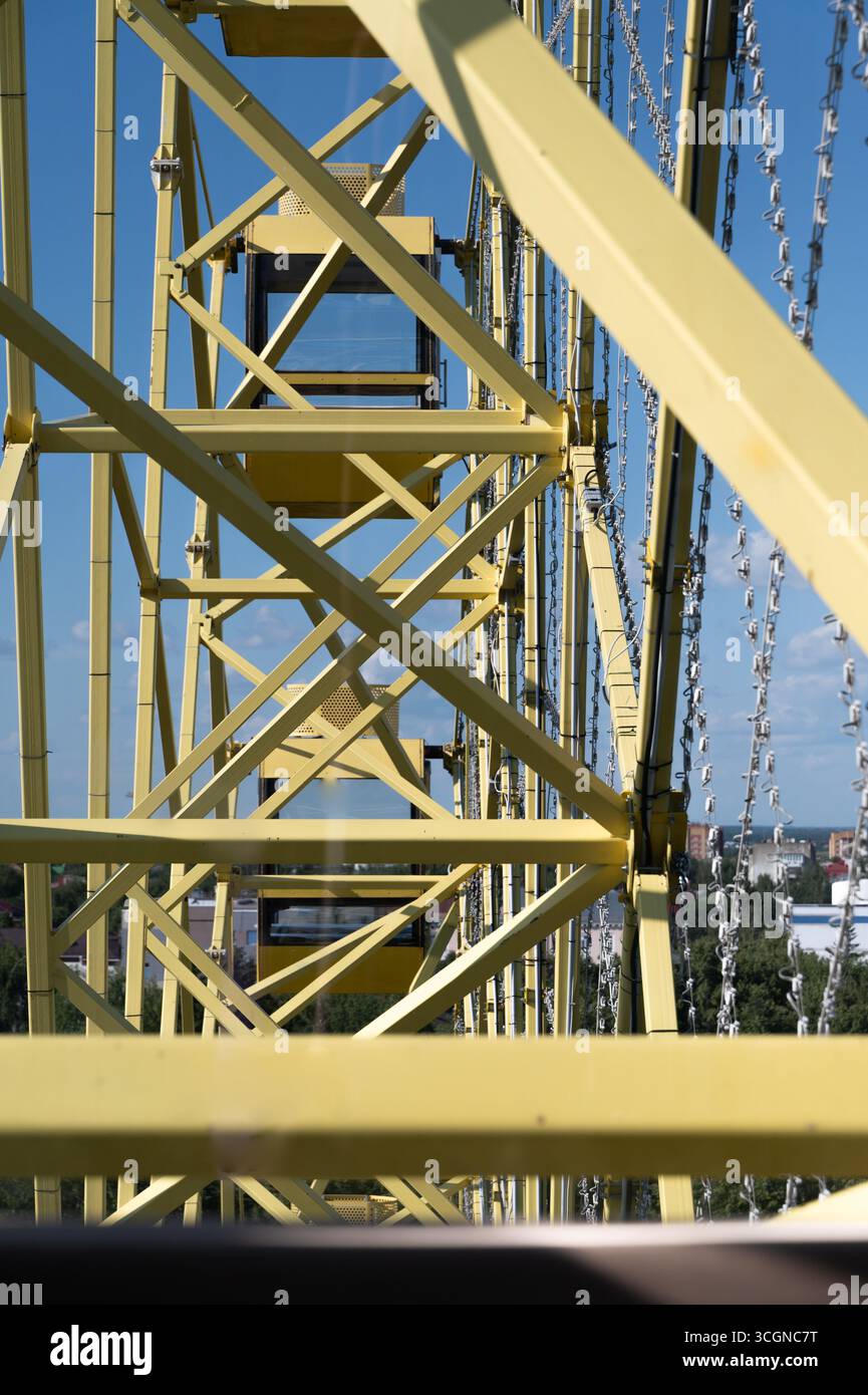 Une vue rapprochée détaillée montrant un cadre structurel de soutien des grandes roues jaunes contre un ciel bleu vif Banque D'Images