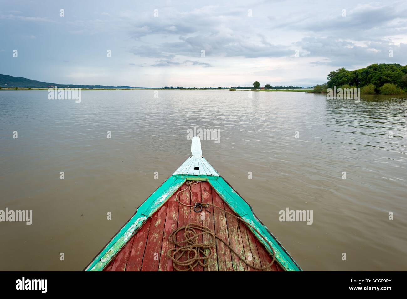 Ayeyarwaddy River from Wooden Bow Mandalay // MANDALAY, Myanmar — la proue d'un bateau fluvial traditionnel en bois navigue sur la rivière Ayeyarwady (également connue sous le nom de rivière Irrawaddy) près de Mandalay. Cette importante voie navigable est la plus longue rivière du Myanmar, coulant environ 2 170 kilomètres (1 350 miles) du nord au sud. Il sert de voie de transport vitale et de ligne de vie économique pour le pays, reliant diverses régions. Mandalay, la deuxième plus grande ville du Myanmar, est un centre économique et culturel majeur situé sur la rive est de l'Ayeyarwady. La rivière est centrale à la vie quotidienne et Li Banque D'Images