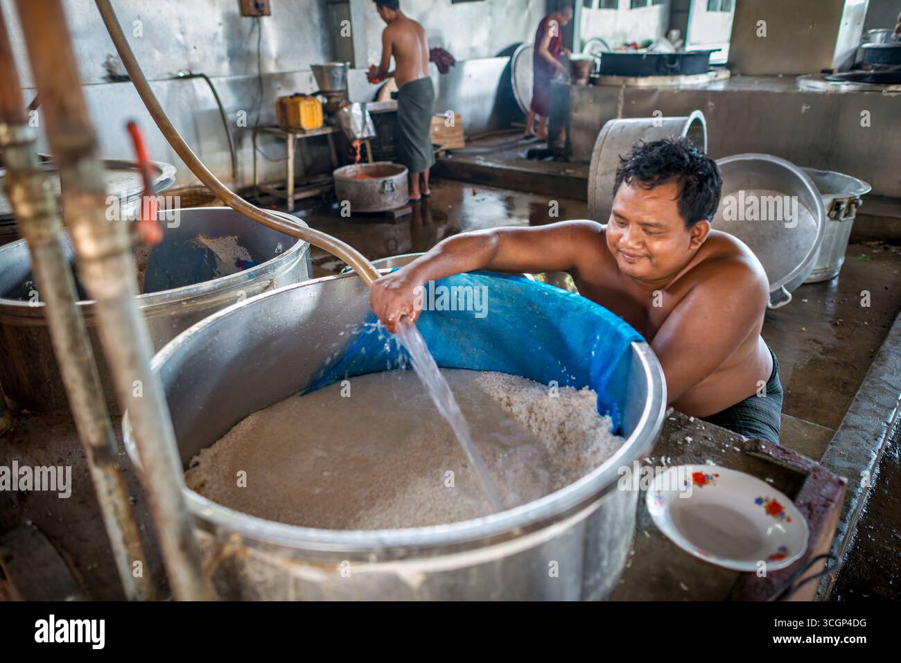 Cuisine du monastère de Mahagandayon cuisson du riz dans de grandes cuves Mandalay Myanmar // MANDALAY, Myanmar — Un ouvrier prépare le riz dans une grande cuve dans la cuisine du monastère de Mahagandayon. Cette préparation quotidienne fournit le déjeuner à des milliers de moines et de novices résidant au monastère. Le monastère de Mahagandayon est l'une des plus grandes et des plus importantes universités monastiques du Myanmar, connue pour son adhésion stricte aux règles monastiques bouddhistes. La cuisine du monastère est un centre animé, préparant des quantités substantielles de nourriture pour nourrir sa grande communauté monastique. Situé dans le canton d'Amarapura, au sud de Mandalay Banque D'Images
