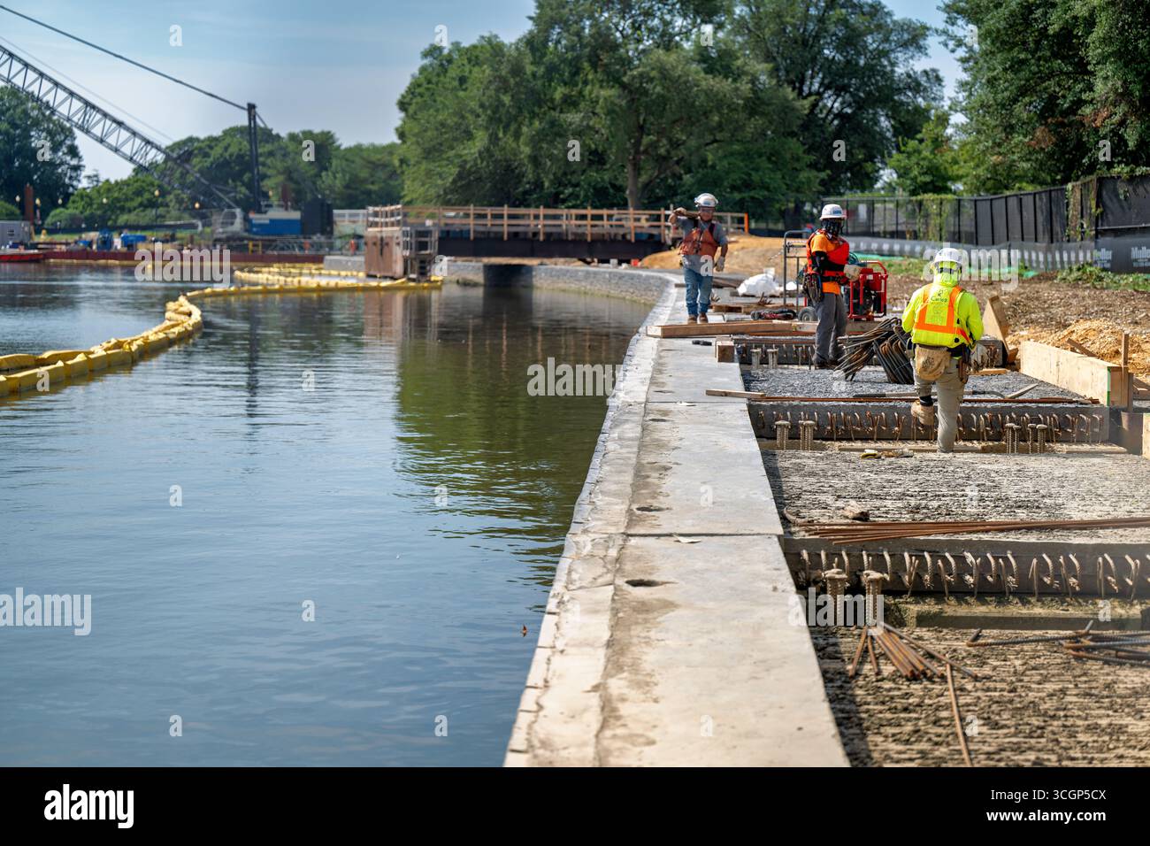 Projet de reconstruction de la digue de Tidal Basin travailleurs de la construction Washington DC USA // WASHINGTON DC — le projet de reconstruction de la digue de Tidal Basin est en cours, comme on l'a vu le 14 août 2025, avec des travailleurs de la construction visibles sur place. Cet effort majeur d'ingénierie vise à remplacer et à élever les digues qui se détériorent autour du bassin de marée, qui coulent en raison des sols mous et des inondations récurrentes dues à l'élévation du niveau de la mer. Le Tidal Basin, un réservoir artificiel situé dans le West Potomac Park, est un point de repère important de Washington DC et abrite le Jefferson Memorial, Martin Luther King, Jr. Memorial, et Banque D'Images Projet de reconstruction de la digue de Tidal Basin travailleurs de la construction Washington DC USA // WASHINGTON DC — le projet de reconstruction de la digue de Tidal Basin est en cours, comme on l'a vu le 14 août 2025, avec des travailleurs de la construction visibles sur place. Cet effort majeur d'ingénierie vise à remplacer et à élever les digues qui se détériorent autour du bassin de marée, qui coulent en raison des sols mous et des inondations récurrentes dues à l'élévation du niveau de la mer. Le Tidal Basin, un réservoir artificiel situé dans le West Potomac Park, est un point de repère important de Washington DC et abrite le Jefferson Memorial, Martin Luther King, Jr. Memorial, et Banque D'Images