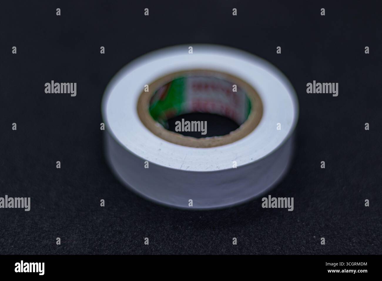 Nouvelle bobine de ruban électrique blanche isolée sur surface noire Banque D'Images